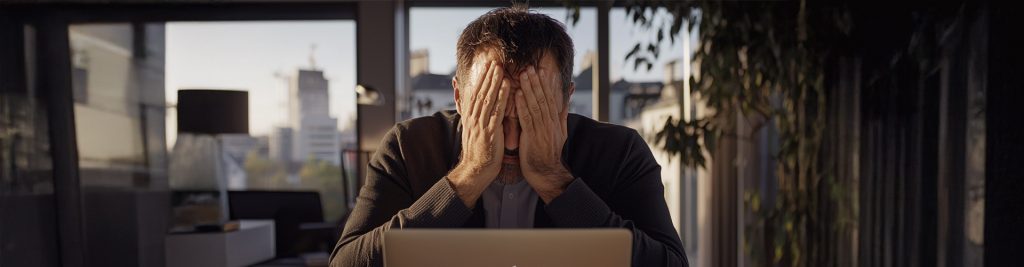 Mann sitzt verzweifelt am Schreibtisch nach Kündigung bei Tesla in Berlin